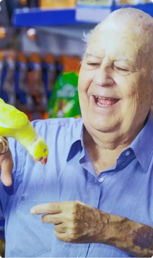 Senhor sorridente de camisa azul dentro da loja Fumaral